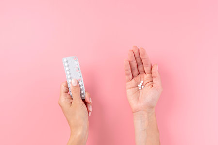 Female hands hold blister packs of pills on pink background, top viewの写真素材