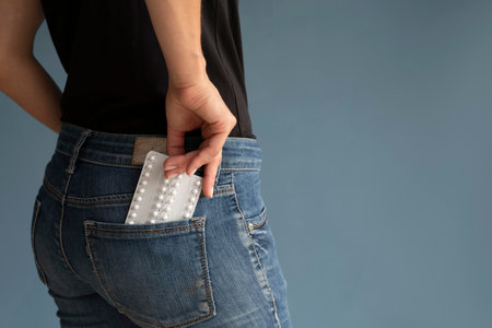 Woman with pills in pocket on color background, closeup. Space for text