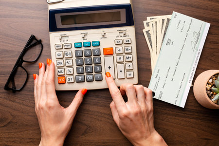 Woman's hands using calculator on wooden table. Business and finance concept