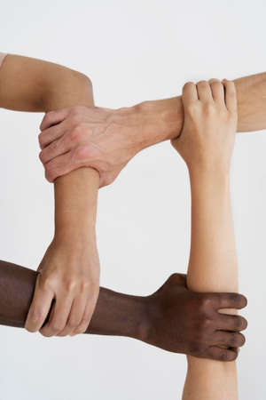 Cropped view of multicultural friends holding hands while standing against white backgroundの写真素材