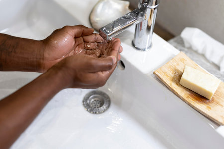 A man washes his hands with soap under the faucet.