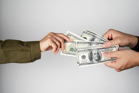 Hands of a man and a woman with dollar bills on a gray backgroundの写真素材