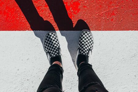 Feet from above on white and red road with shadowの写真素材
