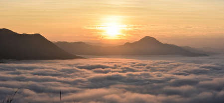 Morning mist and high mountains with orange skyの写真素材