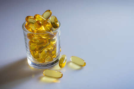 vitamins or fish oil capsule on small glass and clear backgroundの写真素材