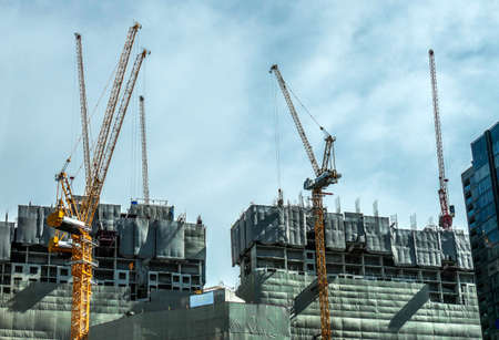Building crane and buildings under construction and cloudy sky, Bangkok Thailandのeditorial素材