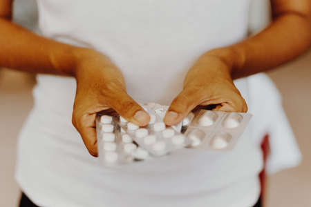 closeup of woman hands holding packaged pillsの写真素材