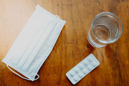 protective mask A glass of water and packaged pills on wooden backgroundの写真素材