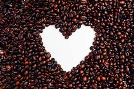 Coffee beans arranged in the shape of a heart on white background top viewの写真素材