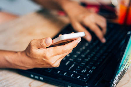 Woman hands working using smart phone and notebook computer, woman hands using smartphone , workplace using technology.の写真素材
