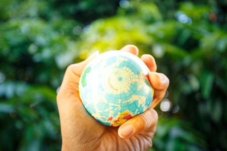 Hand holding world ball on green bokeh backgroundの写真素材