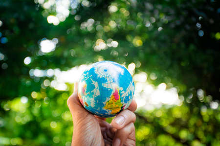 Hand holding world ball on green bokeh backgroundの写真素材