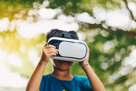 Fascinated little boy using VR virtual reality goggles. outdoorの写真素材