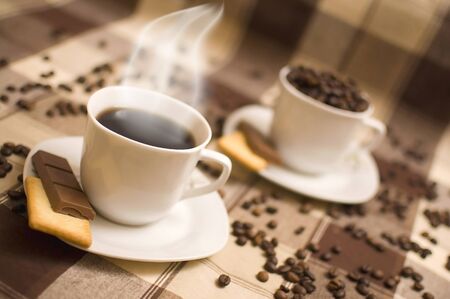 Cups with saucers of coffee hot grains chocolate tablecloth cookies .の写真素材
