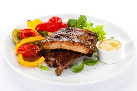Meat on ribs grilled vegetables baked sauce greens white background .の写真素材