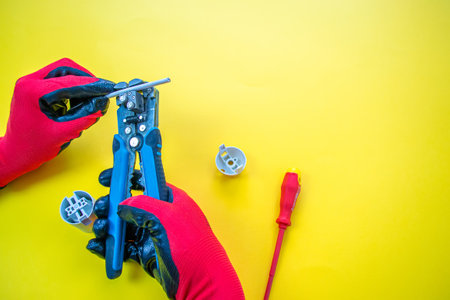 Electrician peeling off insulation from wires - closeup on hands and pliersの写真素材