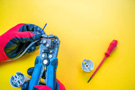 Electrician peeling off insulation from wires - closeup on hands and pliersの写真素材