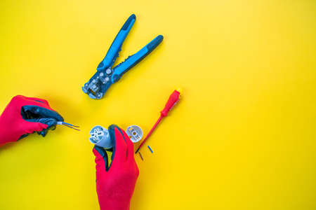 Electrician peeling off insulation from wires - closeup on hands and pliersの写真素材
