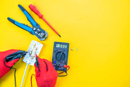 Electrician peeling off insulation from wires - closeup on hands and pliersの写真素材