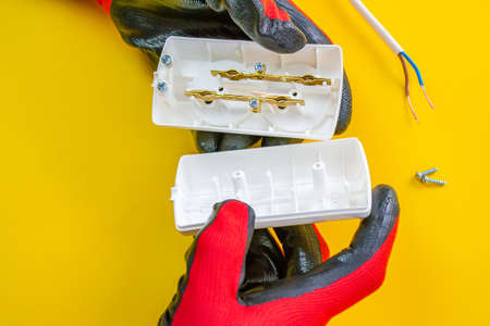 Electrician peeling off insulation from wires - closeup on hands and pliersの写真素材