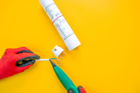 Electrician peeling off insulation from wires - closeup on hands and pliers