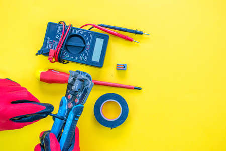 Electrician peeling off insulation from wires - closeup on hands and pliersの写真素材