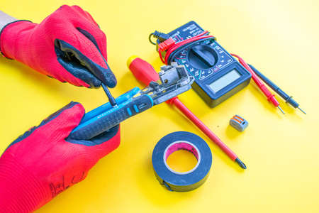 Electrician peeling off insulation from wires - closeup on hands and pliersの写真素材