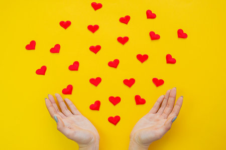 Hands on a yellow background with a heart, love. Selective focus.の写真素材