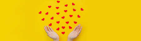 Hands on a yellow background with a heart, love. Selective focus.の写真素材