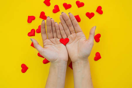 Hands on a yellow background with a heart, love. Selective focus.の写真素材