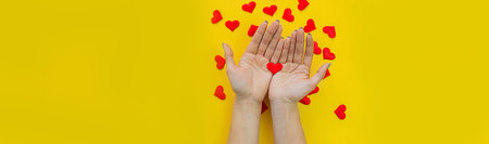 Hands on a yellow background with a heart, love. Selective focus.の写真素材
