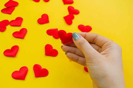 Hands on a yellow background with a heart, love. Selective focus.の写真素材