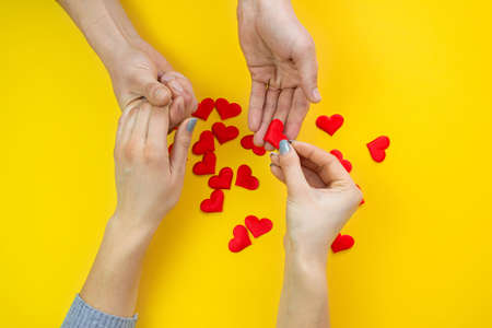 Hands on a yellow background with a heart, love. Selective focus.の写真素材