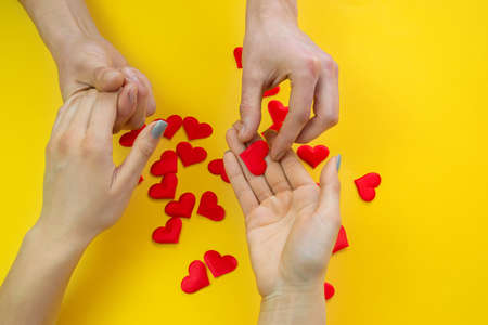 Hands on a yellow background with a heart, love. Selective focus.の写真素材