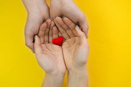 Hands on a yellow background with a heart, love. Selective focus.の写真素材