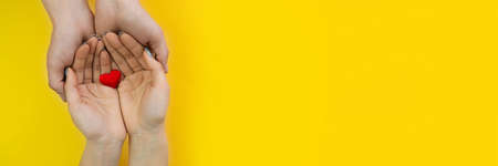 Hands on a yellow background with a heart, love. Selective focus.の写真素材