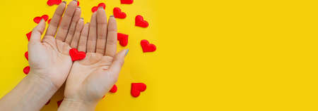 Hands on a yellow background with a heart, love. Selective focus.の写真素材