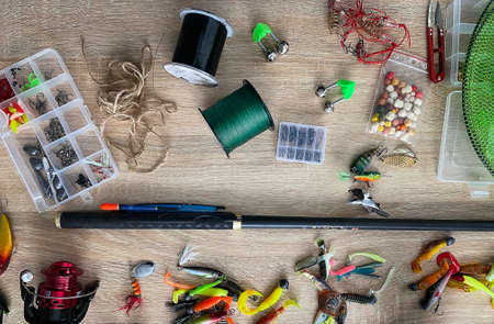 Spinning rod, reel and fishing baits isolated on wooden background, top viewの写真素材