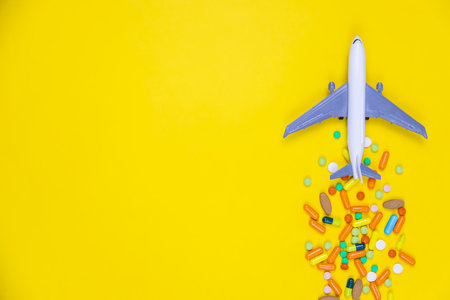 model airplane with multicolored pills from motion sickness close-up on a yellow background. concept illness in travel.selective focusの写真素材