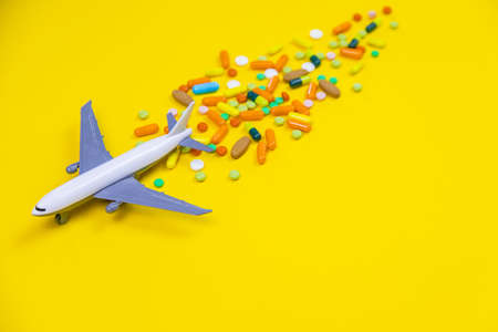 model airplane with multicolored pills from motion sickness close-up on a yellow background. concept illness in travel.selective focusの写真素材