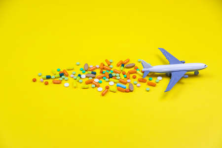 model airplane with multicolored pills from motion sickness close-up on a yellow background. concept illness in travel.selective focusの写真素材