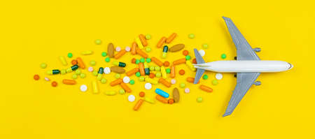 model airplane with multicolored pills from motion sickness close-up on a yellow background. concept illness in travel.selective focusの写真素材