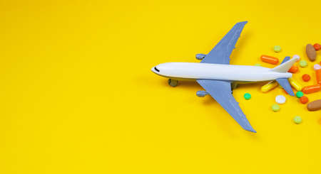 model airplane with multicolored pills from motion sickness close-up on a yellow background. concept illness in travel.selective focusの写真素材