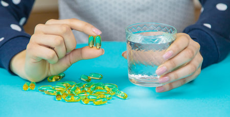 Omega 3 fish oil capsules spilling out of a bottle on a blue background.の写真素材