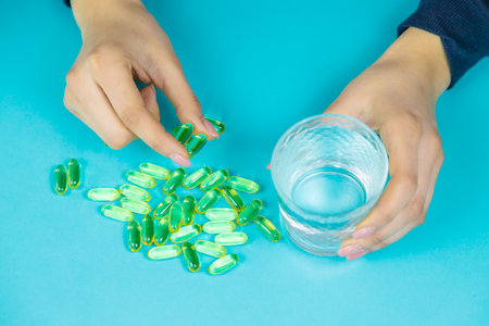 Omega 3 fish oil capsules spilling out of a bottle on a blue background.の写真素材