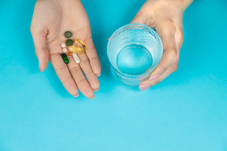 Omega 3 fish oil capsules spilling out of a bottle on a blue background.の写真素材