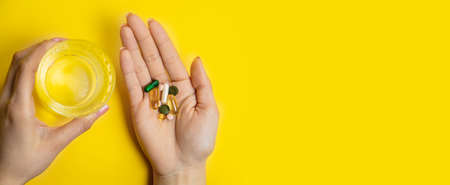 hands on yellow background, pills water cure virus.の写真素材