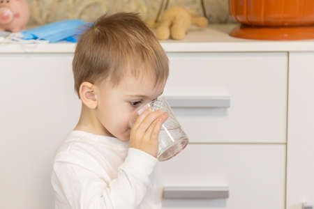 The child drinks water from a glass. Selective focus.の写真素材
