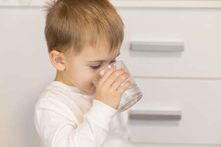 The child drinks water from a glass. Selective focus.の写真素材