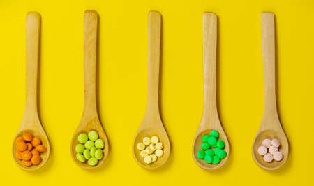 Mixed herbal tablets on a wooden spoon. Food supplement.の写真素材